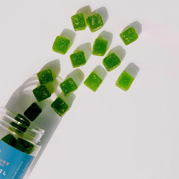 Green gummies spilling from clear jar
