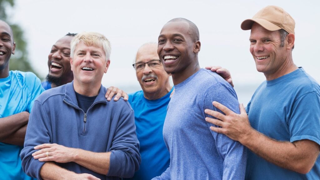 Vibrant group of diverse men smiling and enjoying outdoor activities, highlighting community, health, and wellness with focus on fitness and active lifestyle.